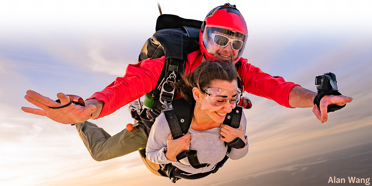 Tandem skydiving student and instructor smiling in freefall